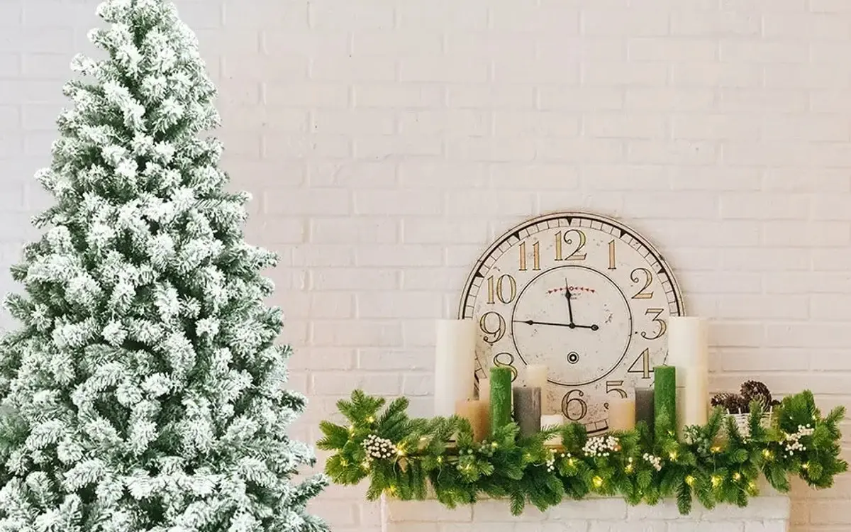 Künstlicher Weihnachtsbaum mit Schnee neben einem Kaminsims